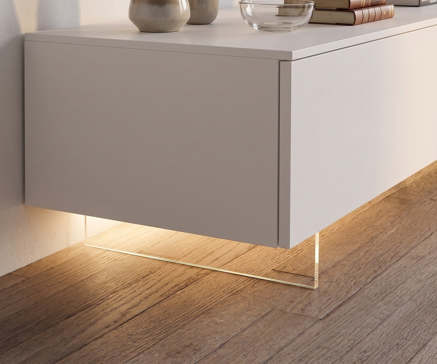Transparante tv-plint van Livitalia voor zwevend effect onder een wit tv-meubel op een houten vloer.