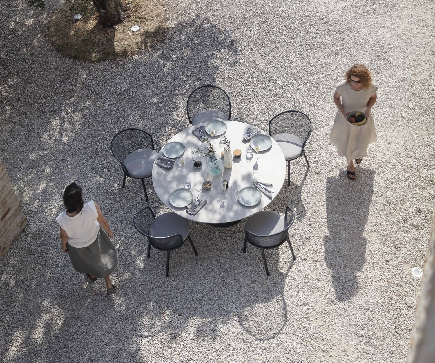 Todus Baza design fauteuil met antraciet onderstel aan een gedekte tuin-eettafel Todus Baza design fauteuil met antraciet onderstel aan een gedekte tuin-eettafel