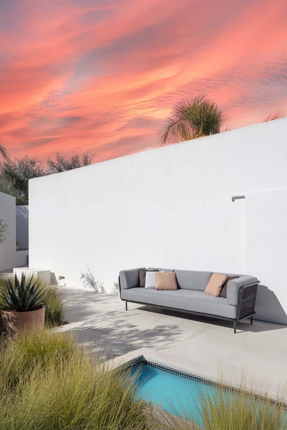 minimalistisch-ontworpen-comfortbank-met-ronde-rugkussens-op-een-mediterraan-ingericht-terras-met-zwembad