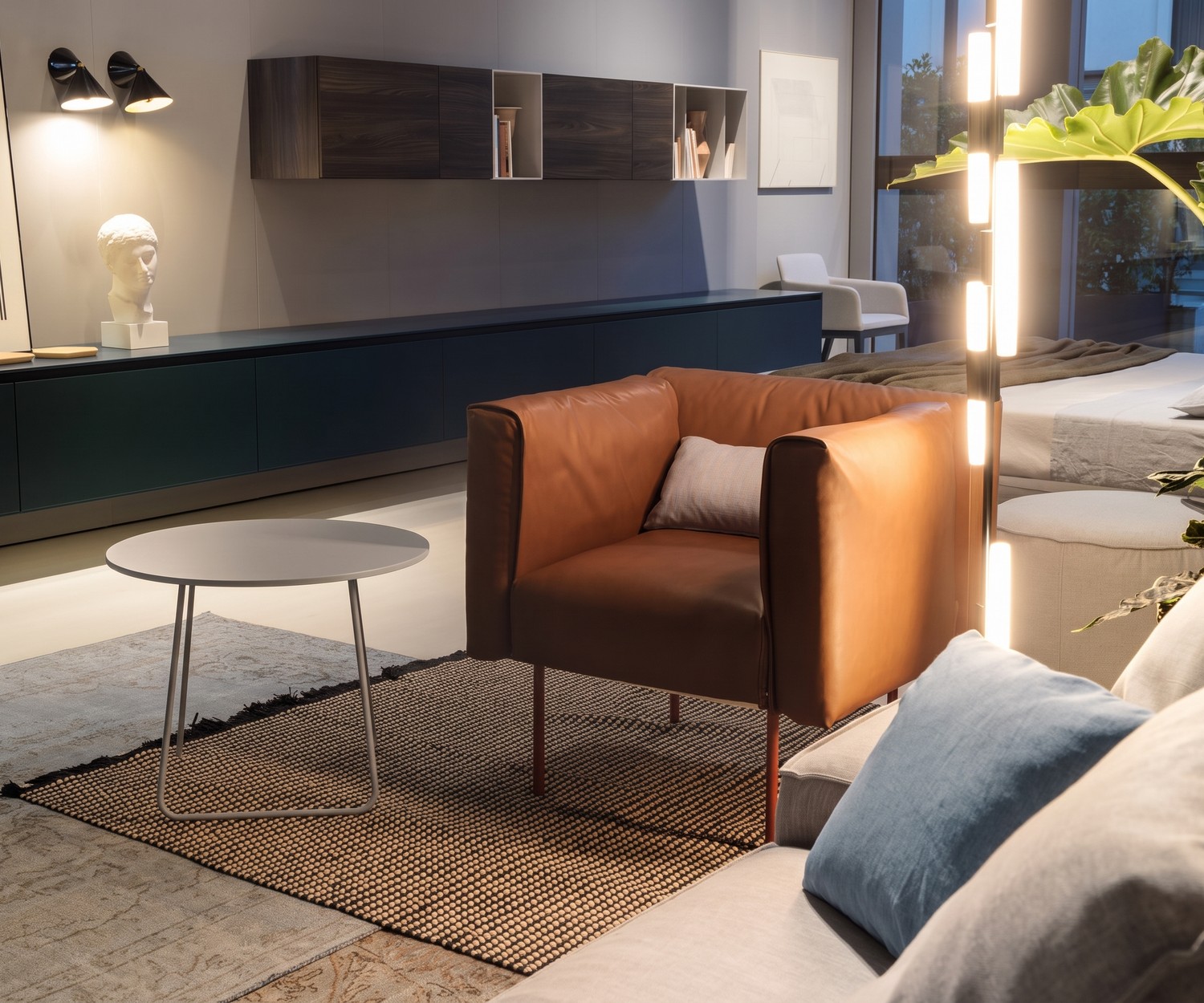 Orbis bijzettafel van Novamobili als ronde salontafel in een moderne woonkamer naast een bruine leren fauteuil.