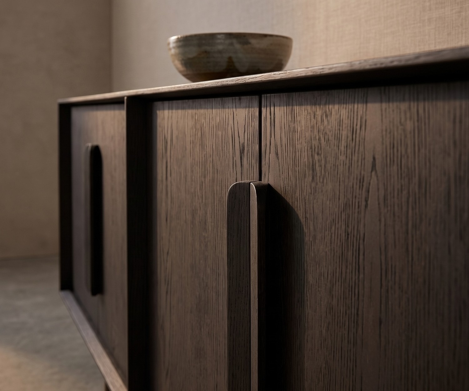 al2 Mobius 003 dressoir van donker eikenhout voor de woonkamer met elegante houten handgrepen en een decoratieve schaal.