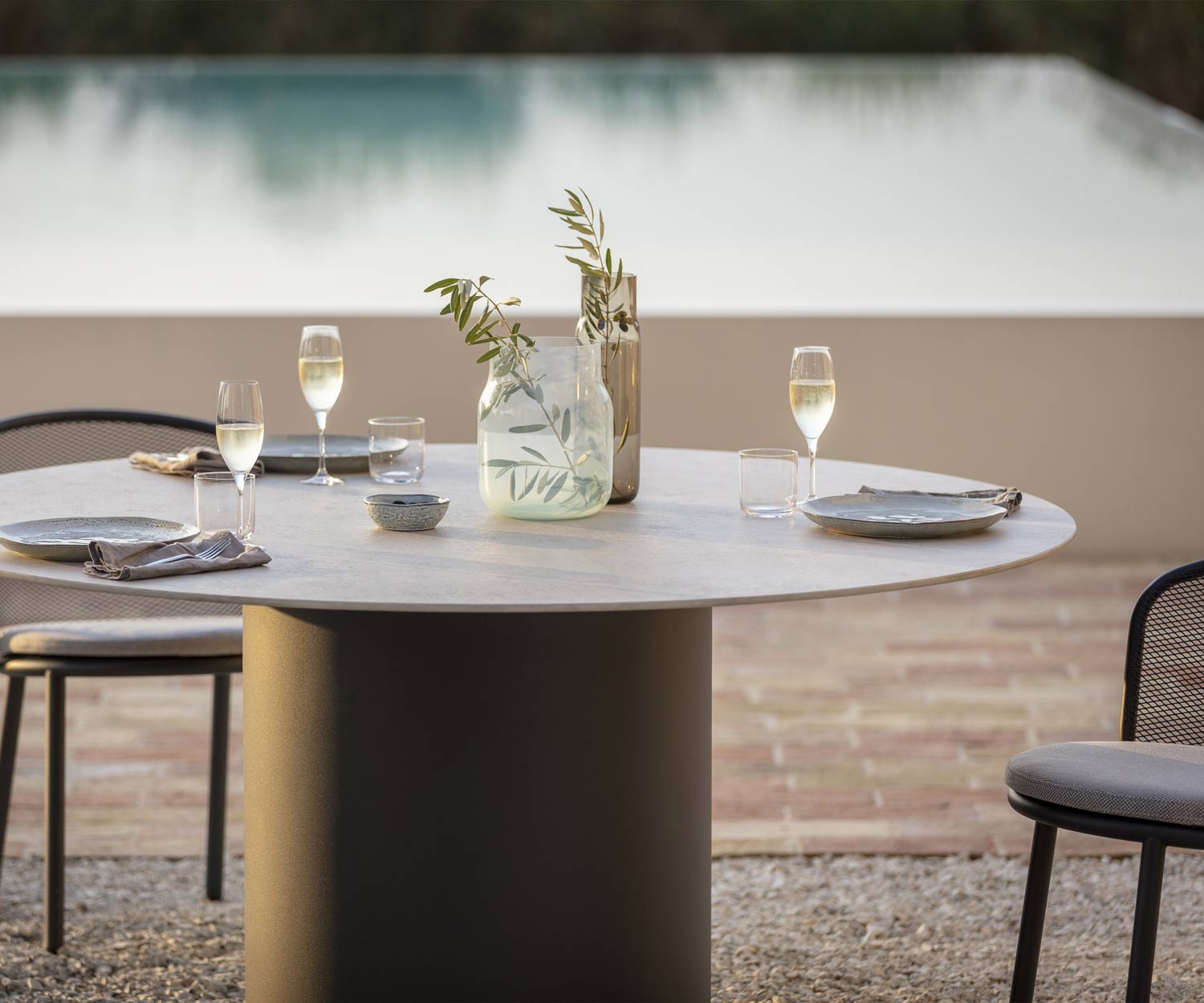 Gedekte eettafel van Todus met grijs keramisch tafelblad bij het zwembad op een grindterras