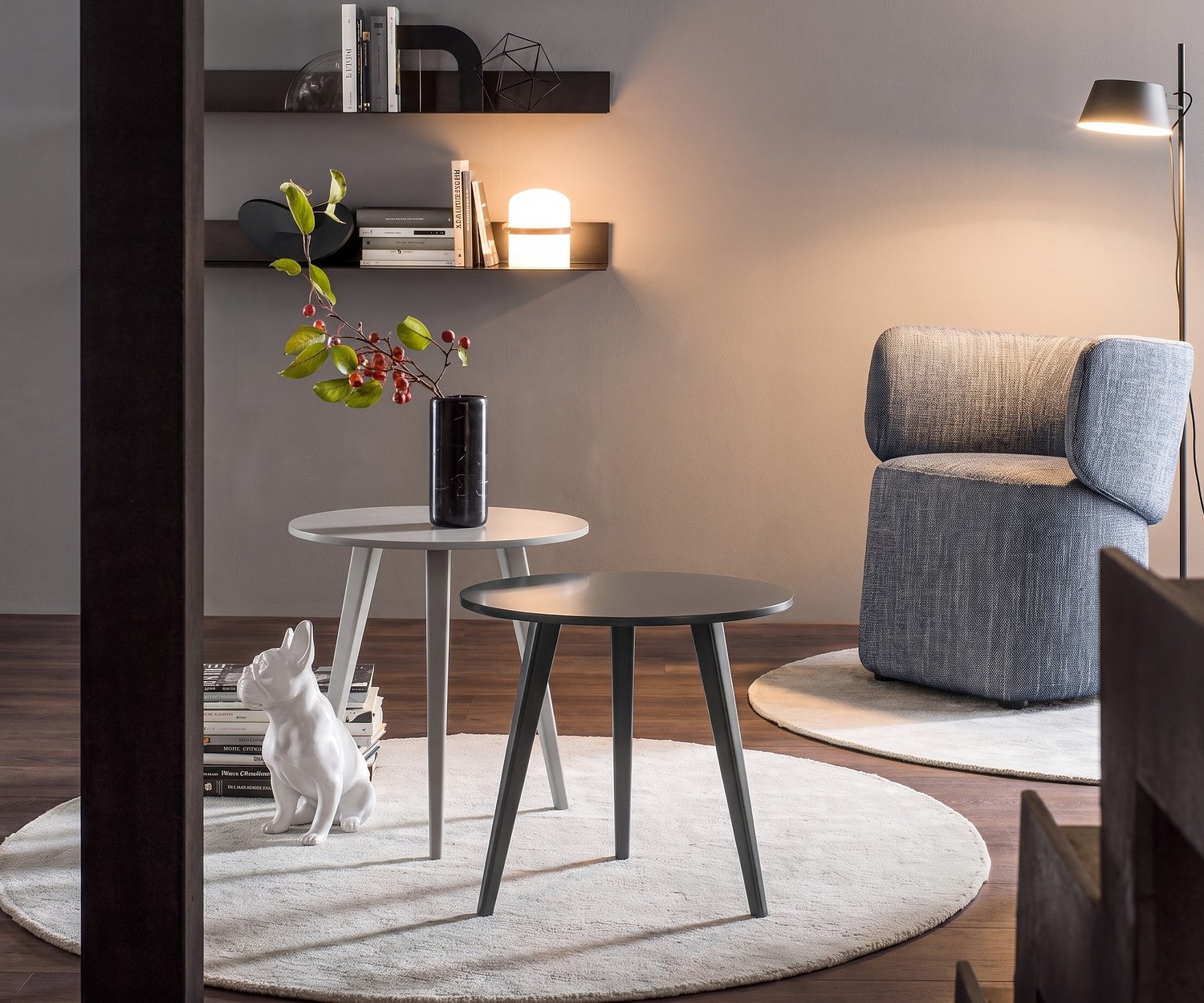 Novamobili Trio design bijzettafel in de woonkamer, moderne grijze driepoot houten tafels op een rond vloerkleed bij fauteuil.