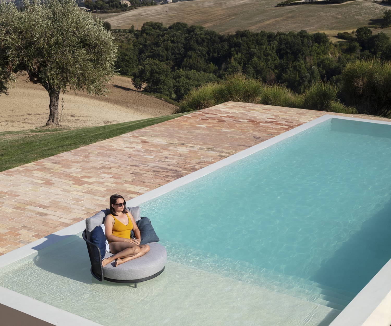 Duurzame Baza Ronde tuinlounge van Todus met de voeten in het zwembad Duurzame Baza Ronde tuinlounge van Todus met de voeten in het zwembad